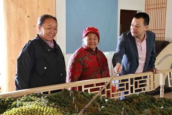 余廷学（右一）在沙盘前为村民讲述吉星村发展规划