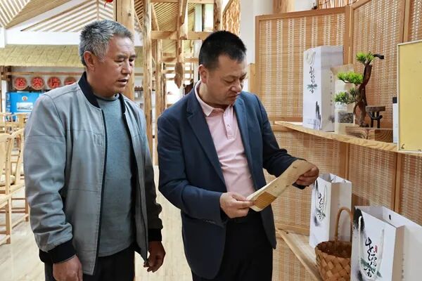 余廷学（右）和村民一起探讨老鹰茶下一步发展规划
